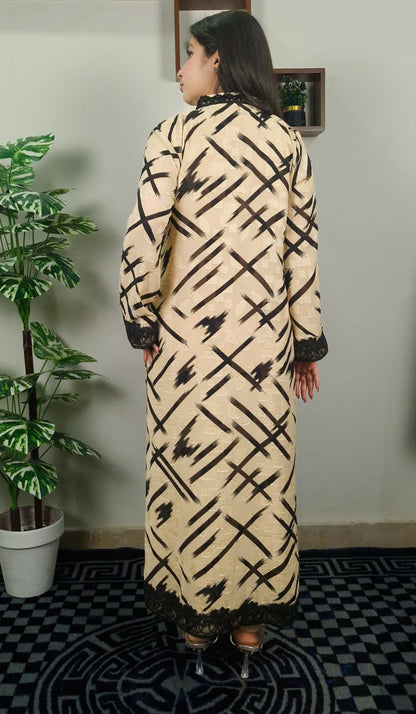 Woman wearing a long, patterned dress standing in a room with a plant and checkered floor
