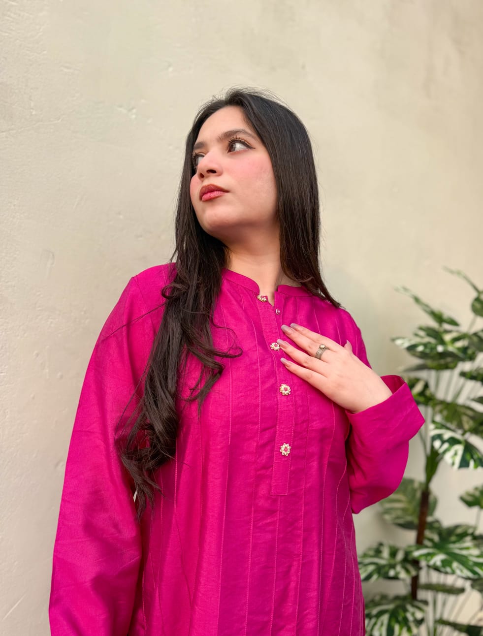 Woman wearing a bright pink traditional outfit against a neutral background
