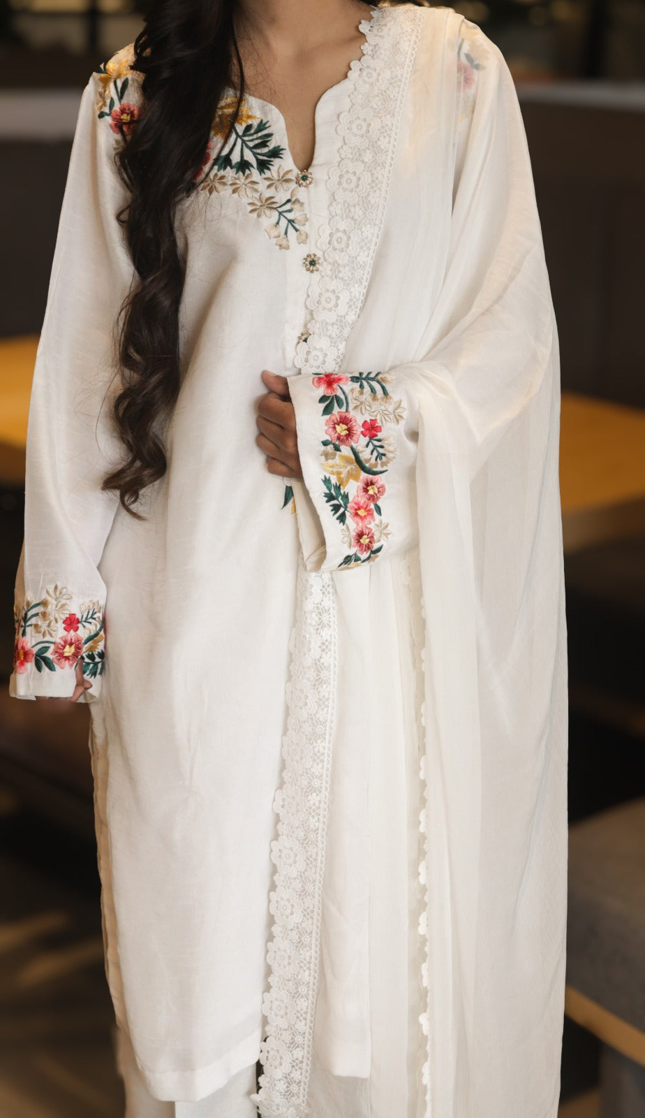 White embroidered outfit with floral patterns on a blurred background