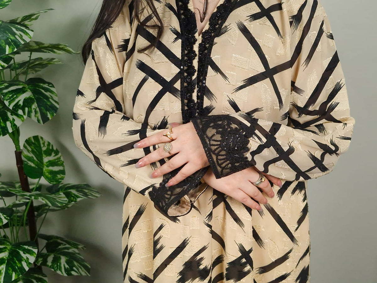 Girl wearing a beige and black patterned outfit with lace details, standing next to a plant