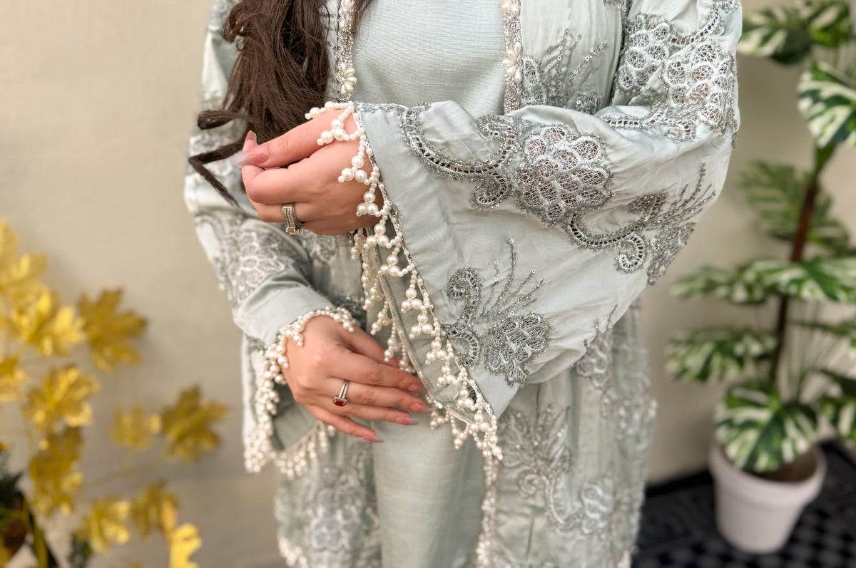 Girl wearing a light blue embroidered outfit with floral decorations in the background